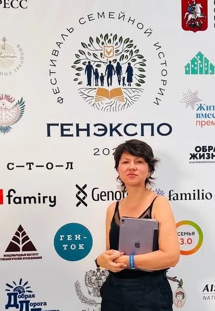 Автор с планшетом у пресс-волла фестиваля семейной истории ГенЭкспо